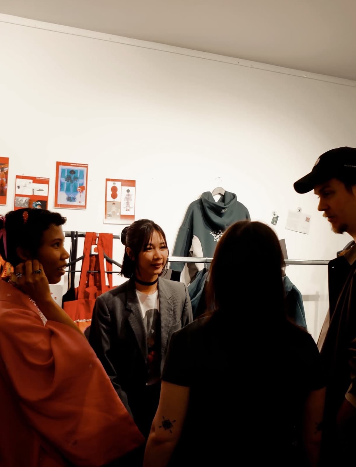 Four people talking together in front of a clothing rail